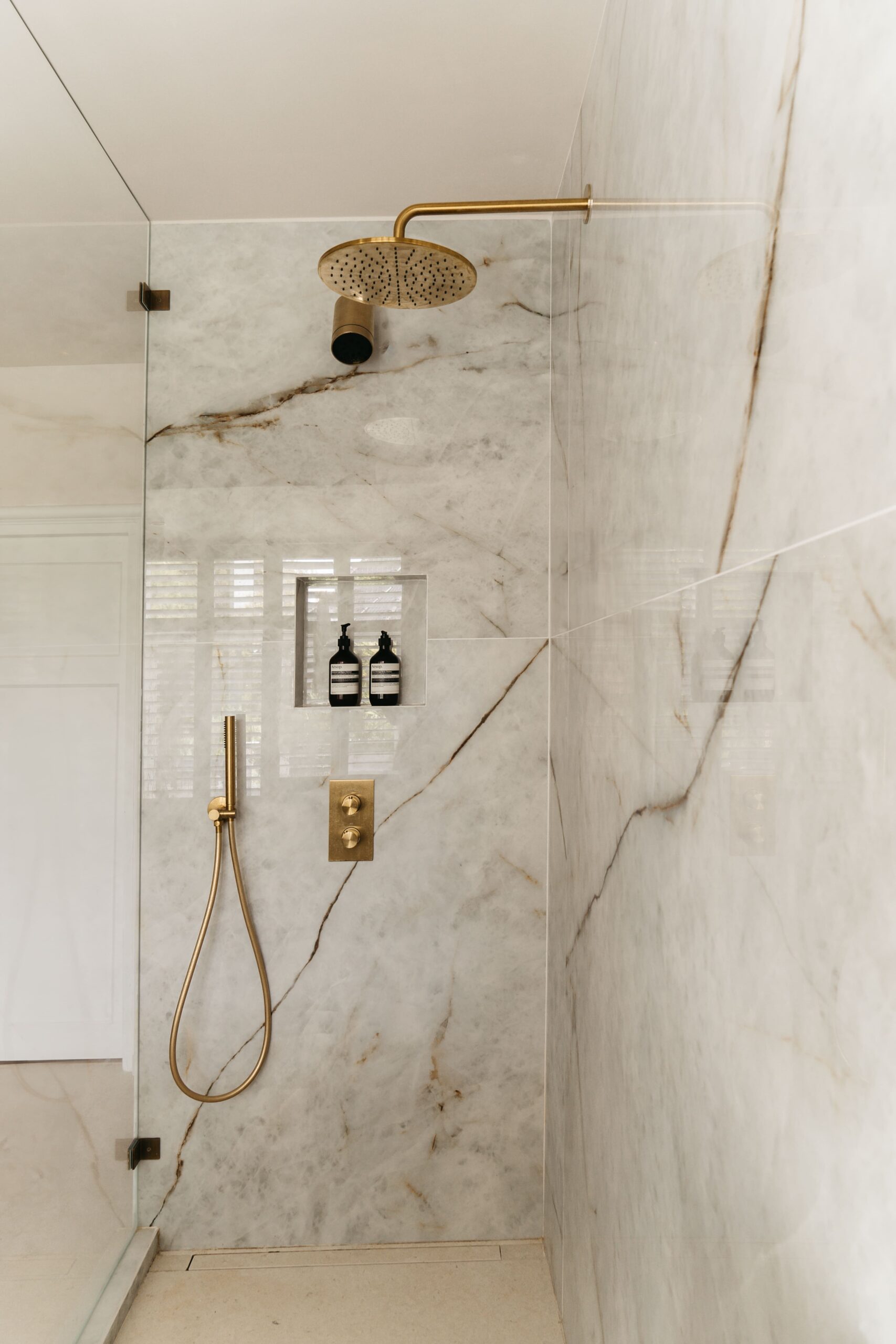 Inloopdouche met grootformaat Himalaya Crystal marmerlook tegels, geborsteld gouden regendouche, handdouche en glazen douchewand