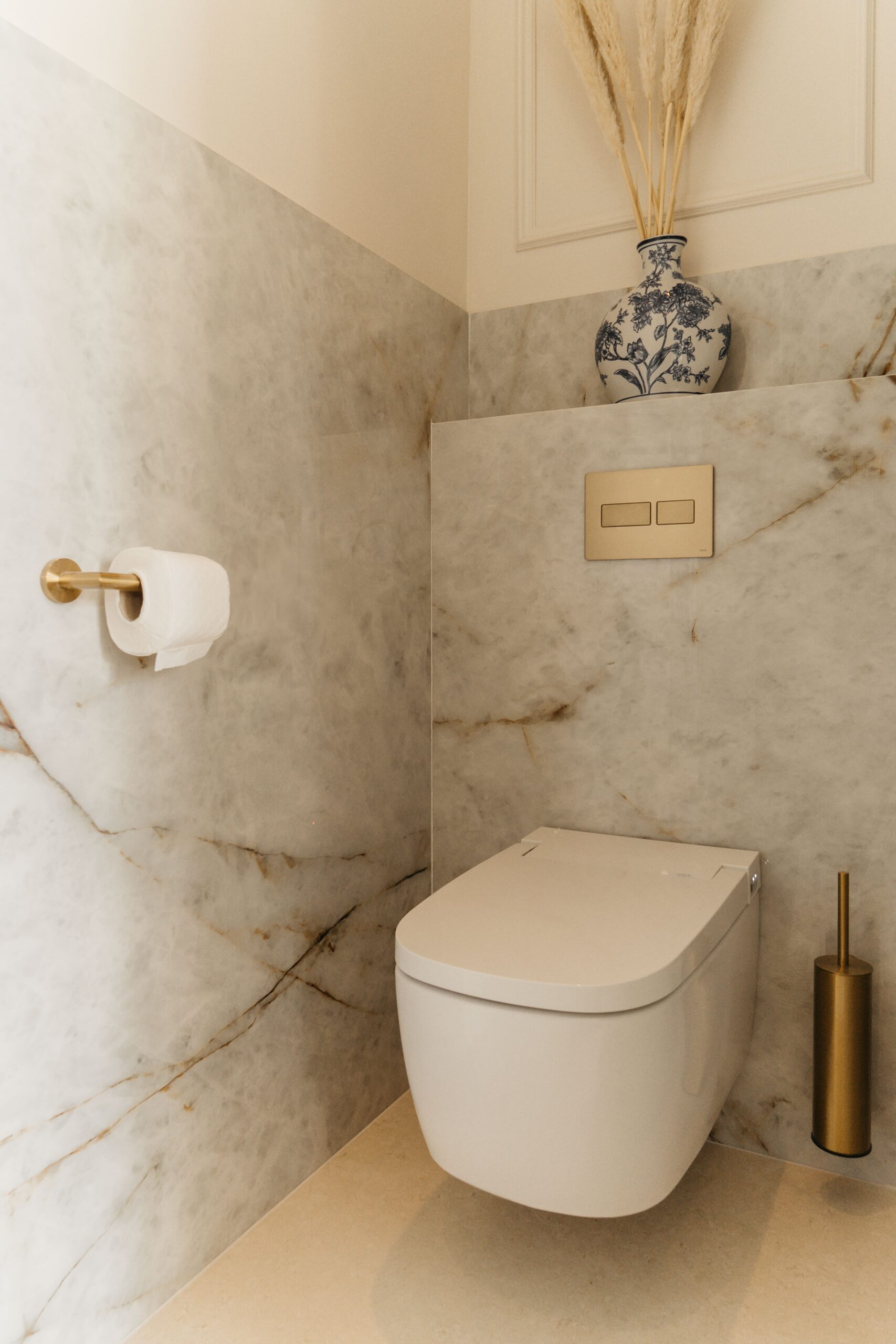 Luxe toiletruimte met Vitra V-Care douche-wc, TECE bedieningsplaat in geborsteld messing en marmerlook wandtegels